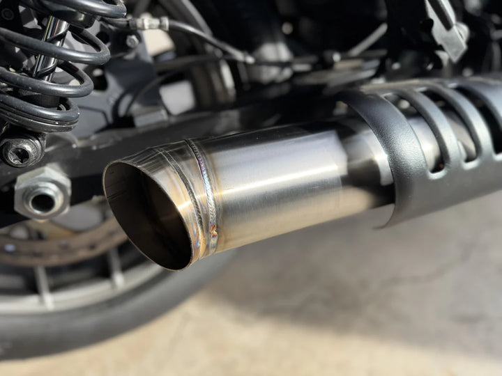 Close up of slip-on muffler exhaust system for a Harley Davidson Nightster, made of stainless steel, installed on a motorcycle