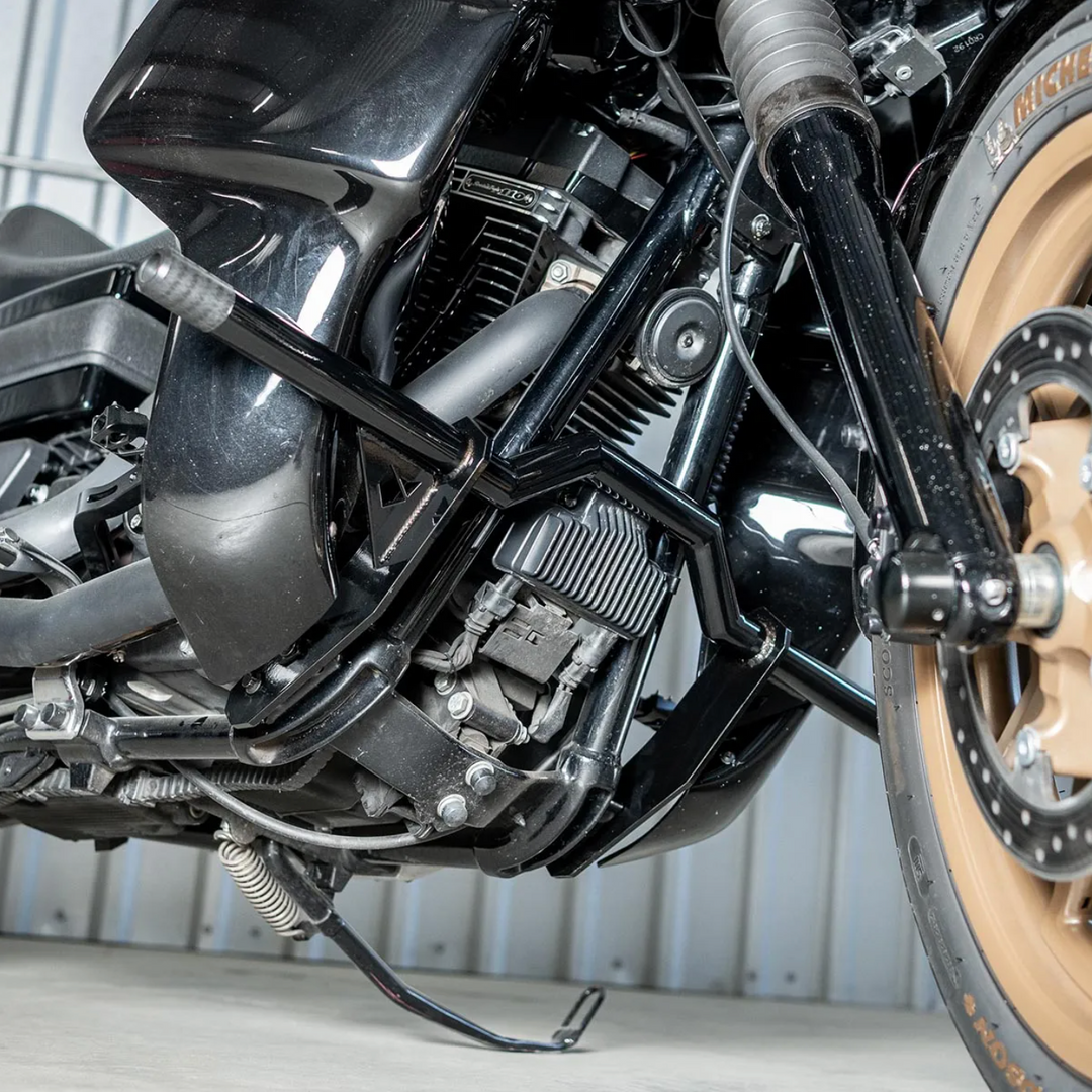 A black motorcycle crash bar installed on a motorcycle, designed to protect the paint job during falls or tipovers.