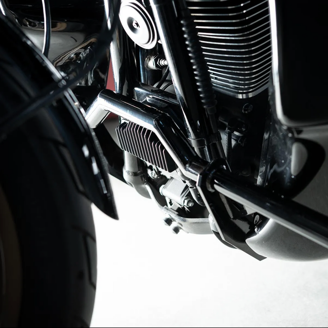 A black motorcycle crash bar installed on a motorcycle, designed to protect the paint job during falls or tipovers.