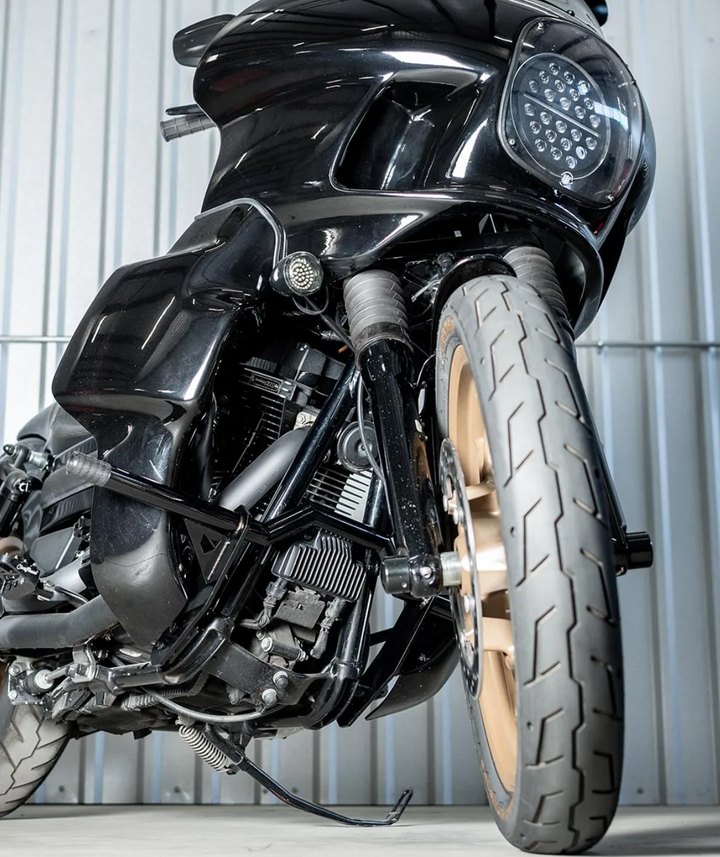 A black motorcycle crash bar installed on a motorcycle, designed to protect the paint job during falls or tipovers.