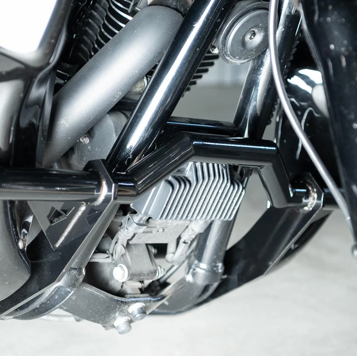 A black motorcycle crash bar installed on a motorcycle, designed to protect the paint job during falls or tipovers.