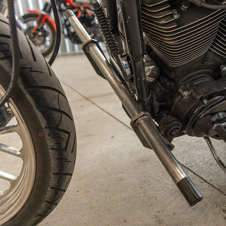 A black metal Dyna Crash Bar designed for motorcycle stunt riding, includes two Delrin sliders, displayed on a white background.