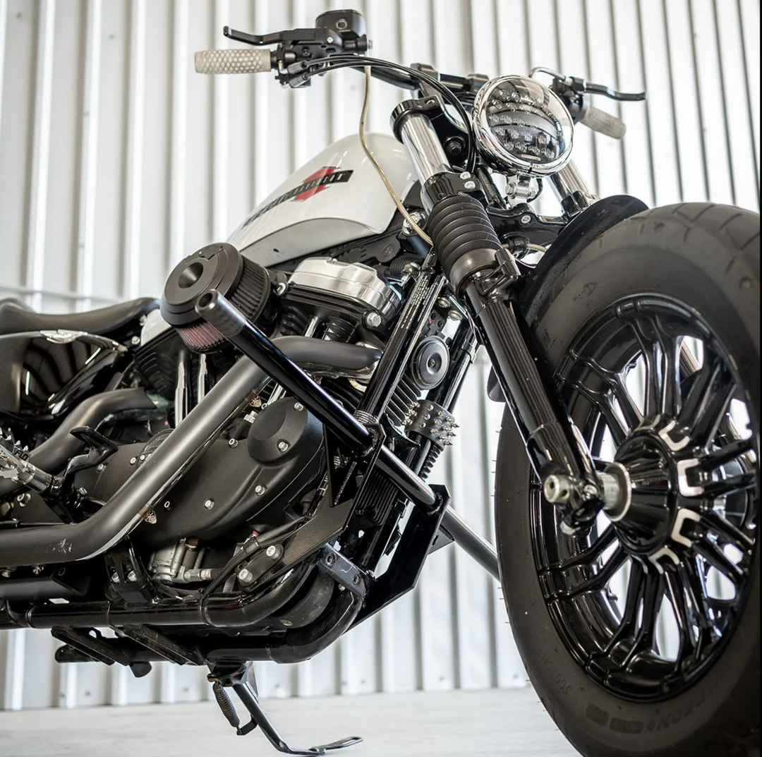 A black front crash bar installed on a Harley Davidson Sportster motorcycle, featuring two Delrin sliders.
