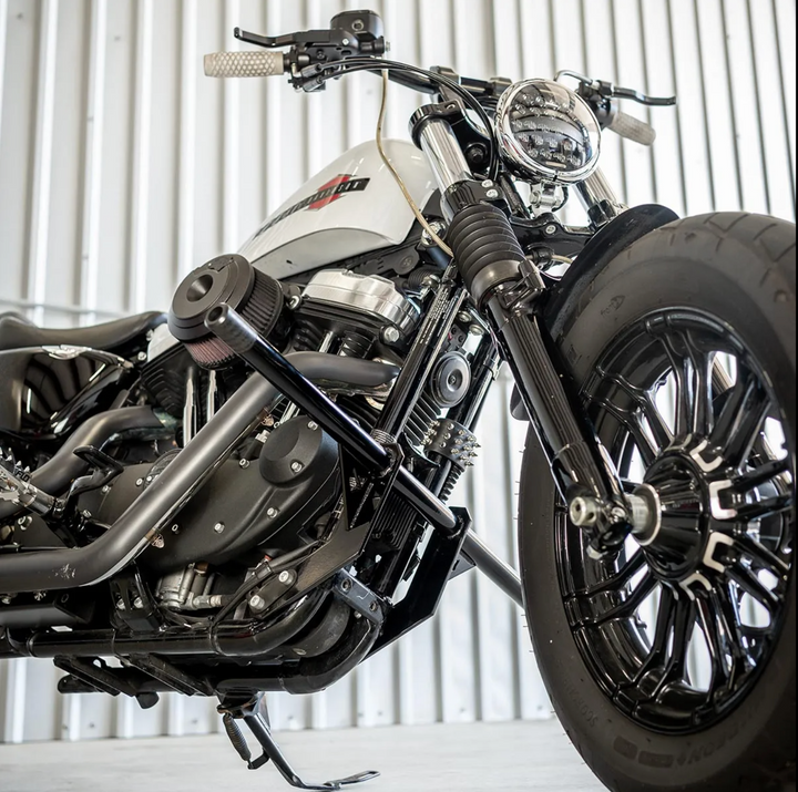 A black front crash bar installed on a Harley Davidson Sportster motorcycle, featuring two Delrin sliders.
